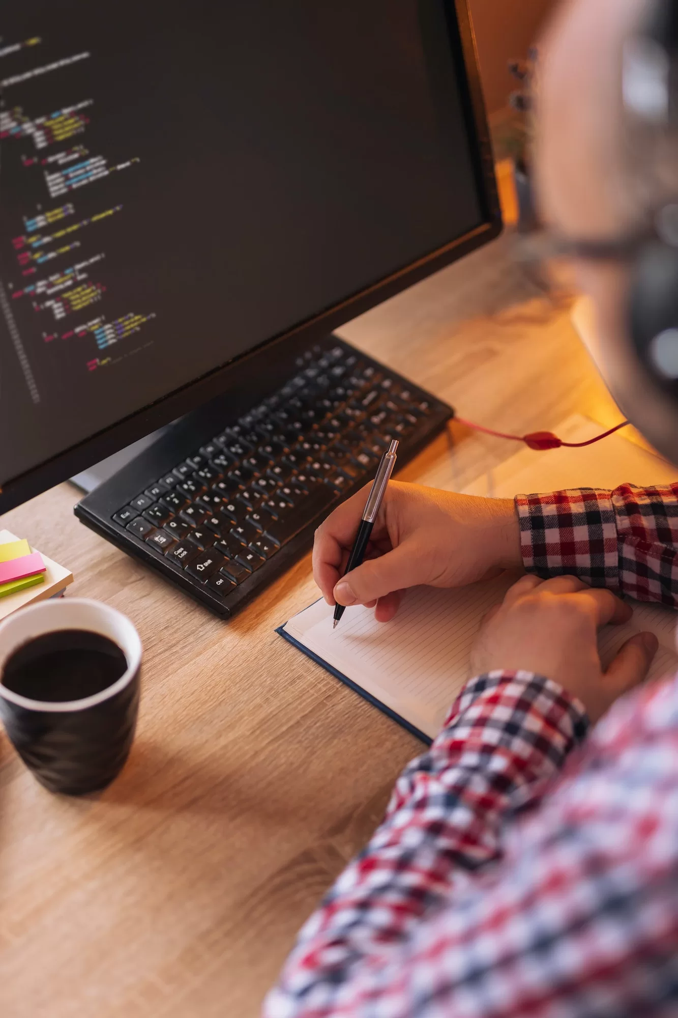 Web developer writing in planner while having conference call